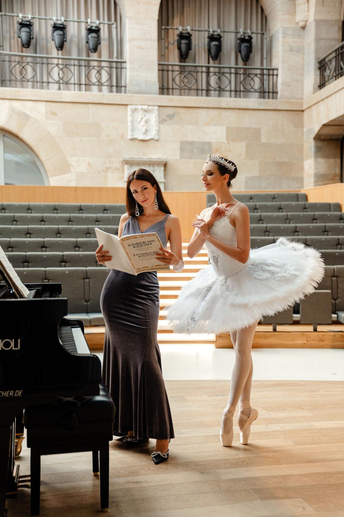Eine Pianistin und eine Balletttänzerin stehen neben einem Konzertflügel.