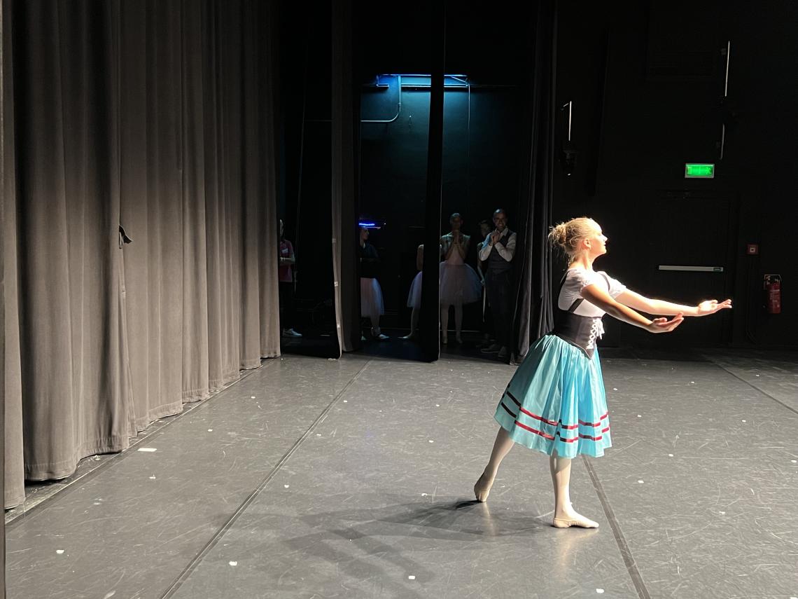 Ein Kind tanzt Ballett auf einer Bühne.