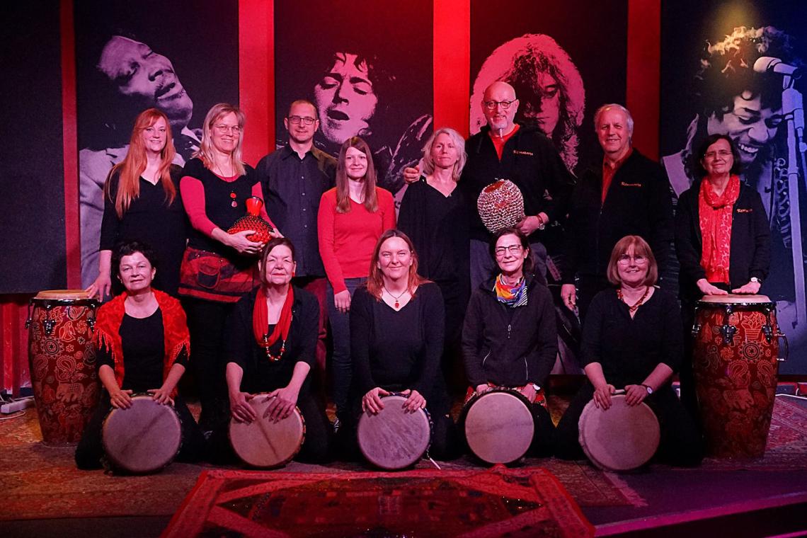 Eine Musikgruppe mit Percussion-Instrumenten posiert für ein Gruppenbild.