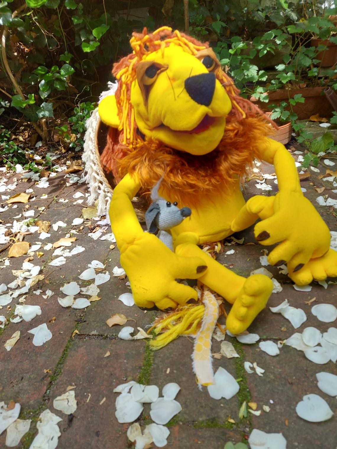 Eine kleine Maus sitzt auf einem Löwen, als Puppen dargestellt.