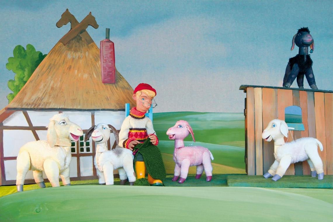 Eine Herde Schafe und die Bäuerin stehen vor einem Bauernhaus im friesischen Stil.