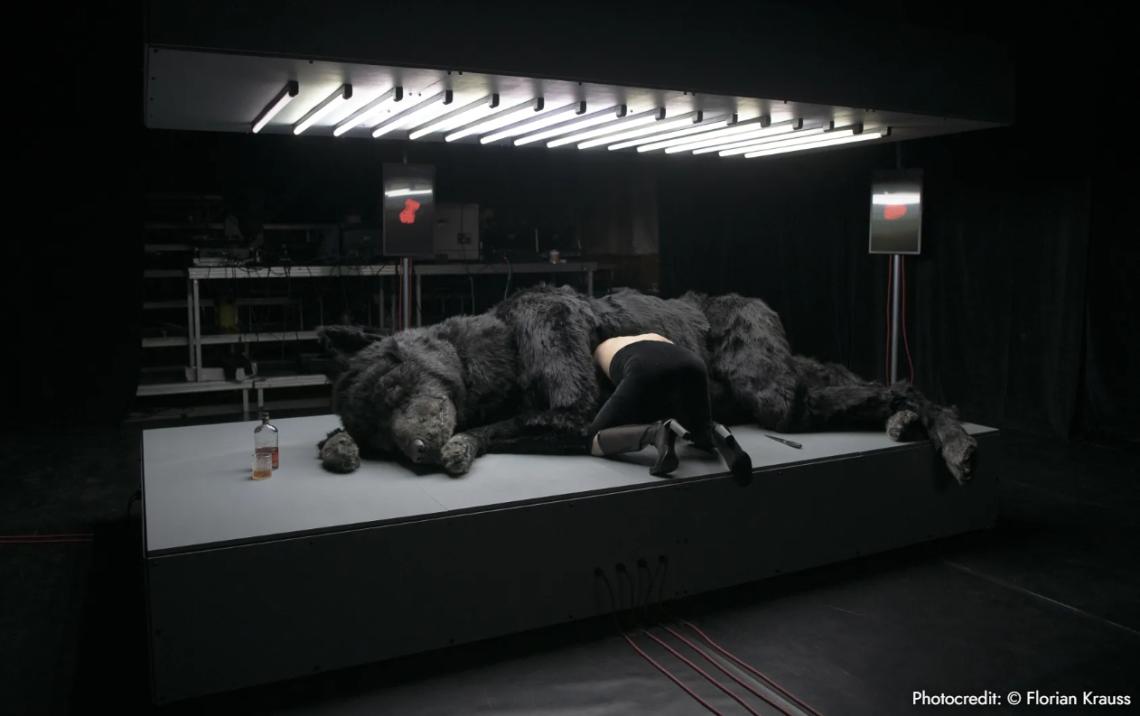 Eine Frau kriecht in den aufgeschnittenen Bauch eines Wolfs hinein.