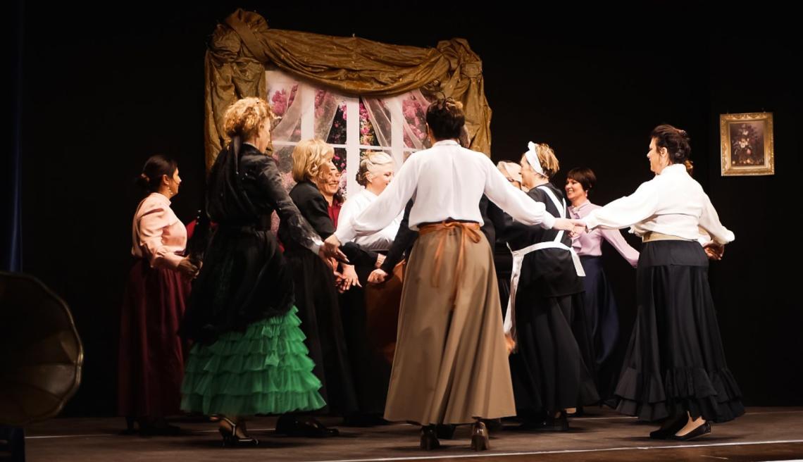 Eine Gruppe von Frauen hält sich im Kreis an den Händen und tanzt.