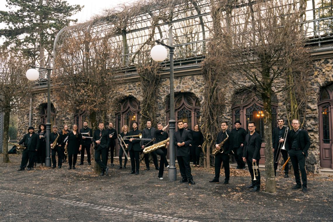 Eine Bigband steht mit ihren Instrumenten vor einer historischen Mauer