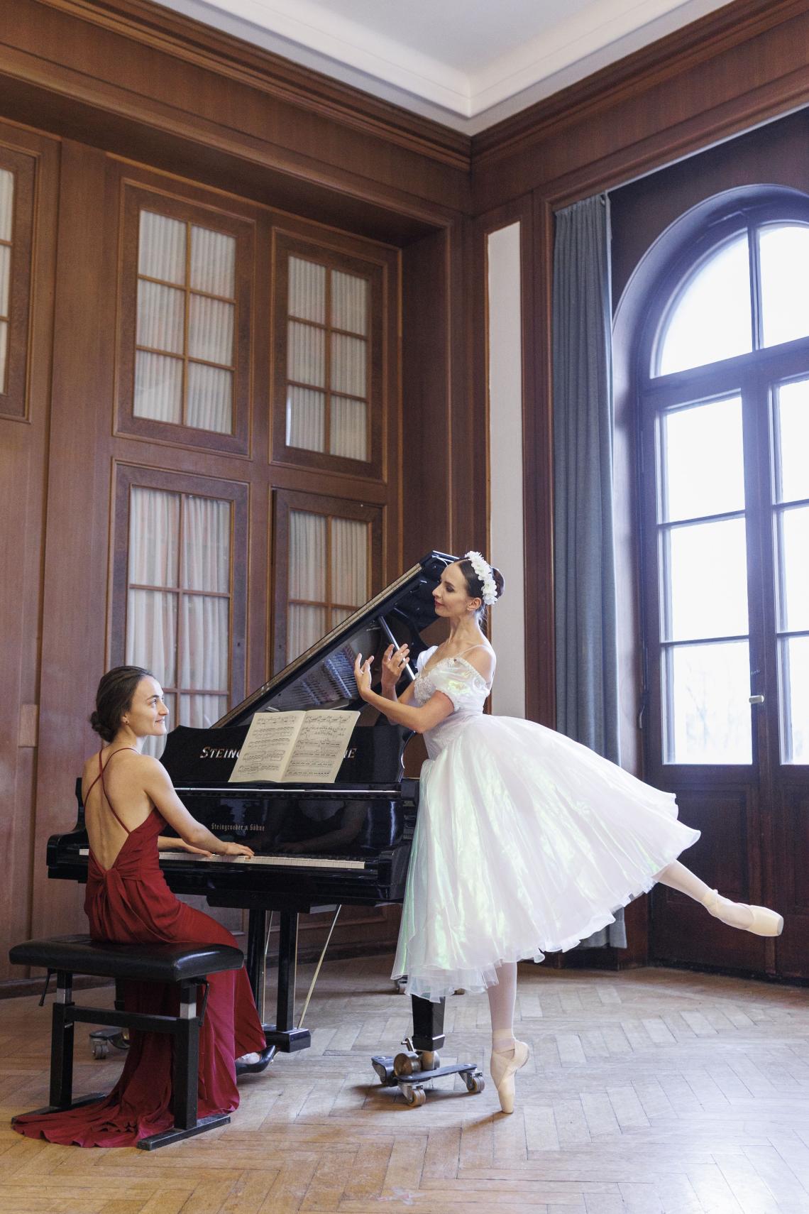 Eine Pianistin sitzt am Flügel, während neben ihr eine Ballerina tanzt.