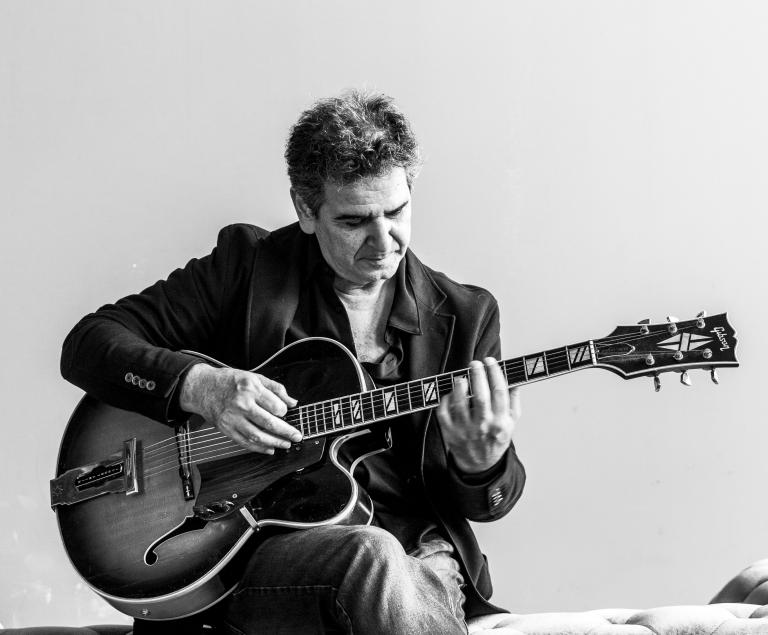 Ein sitzender Mann spielt eine halbakustische Jazzgitarre.