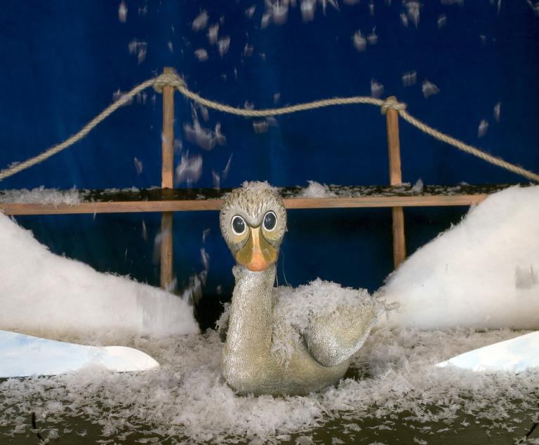 Ein kleiner grauer Vogel sitzt im Schnee.