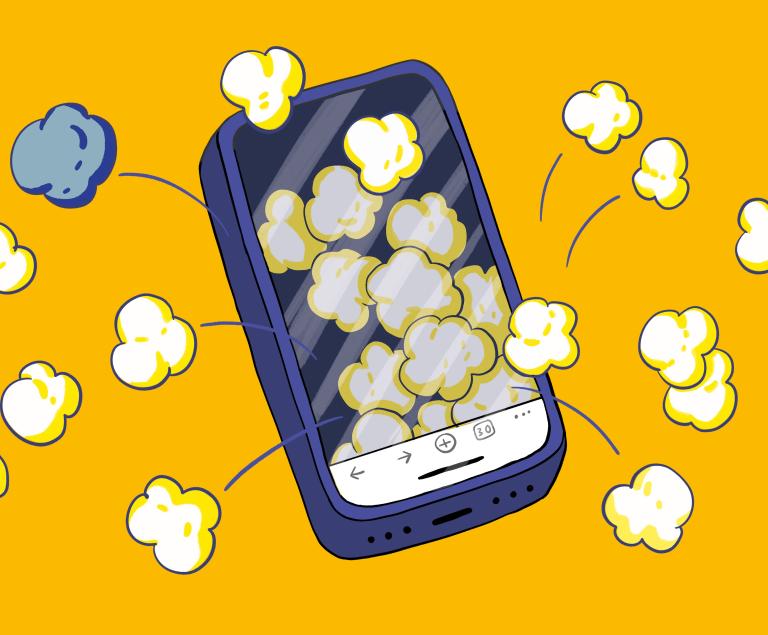 Aus dem Display eines Smartphones springen lauter Popcorn-Körner heraus.