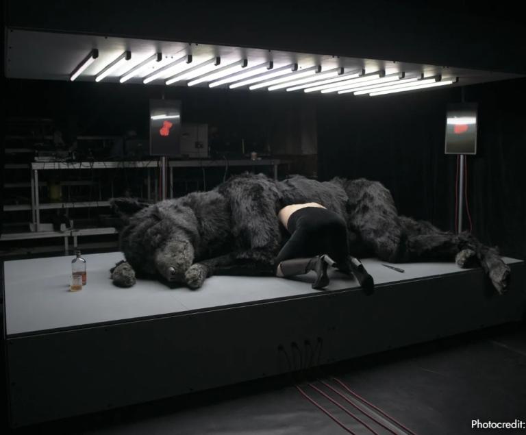 Eine Frau kriecht in den aufgeschnittenen Bauch eines Wolfs hinein.