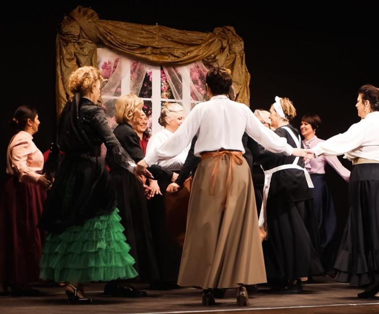 Eine Gruppe von Frauen hält sich im Kreis an den Händen und tanzt.